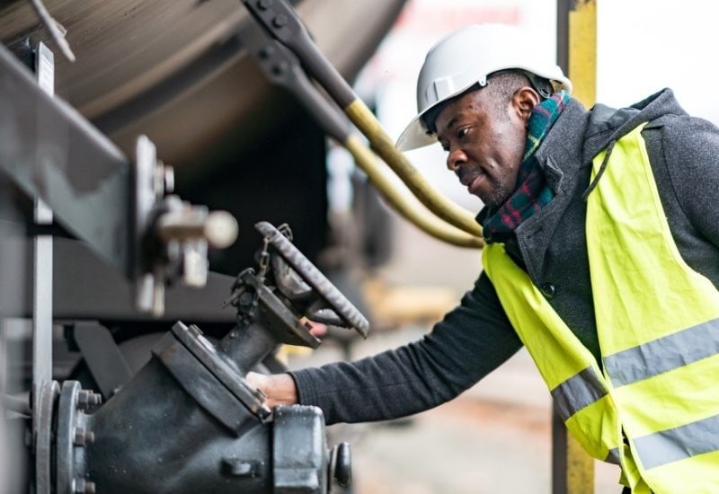Inventory Express Blog Images (8) Railway mechanic inspecting gear on a train, showing the need for railroad oil and lubricant.